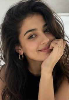 Woman with dark long hair and hoop earrings smiling at the camera
