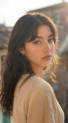 Woman with long wavy hair and hoop earrings in soft golden hour light