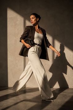 Woman in a blazer and wide leg pants walking in a sunlit room
