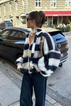 Woman in a striped cardigan and dark jeans standing on a city street