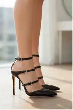 Close up of a person's legs wearing black strappy high heels indoors