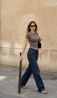 Woman in a crop top and wide leg jeans walking on a street