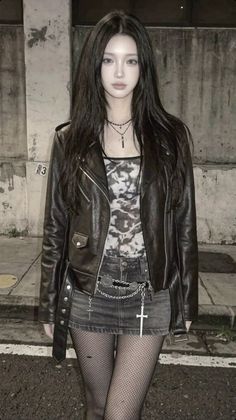 Person with long dark hair wearing a leather jacket and mini skirt outdoors