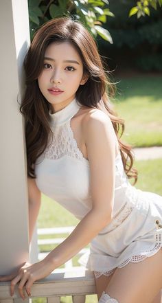 Woman with long brown hair wearing a white top with lace details, posing outdoors