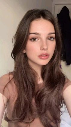 Young woman with long brown hair and natural makeup in an indoor setting