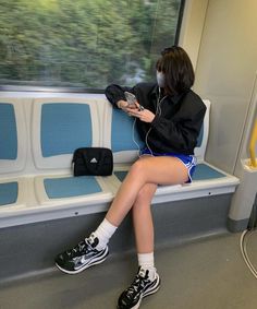 Person with short hair sitting in a subway car, looking out the window