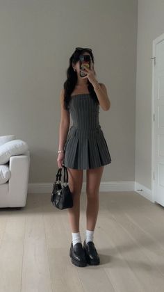 Woman in a pinstripe dress taking a mirror selfie indoors