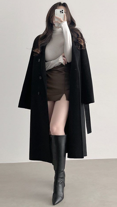 Woman in a black coat, white turtleneck, and brown mini skirt with knee-high boots