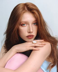 Woman with red hair and freckles wearing a pearl ring, looking at the camera
