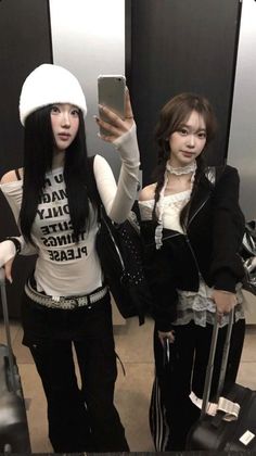 Two women posing for a mirror selfie indoors with luggage