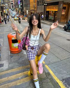 Smiling woman in a plaid skirt and tank top on a city street