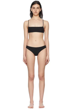 Woman in a black bikini standing against a white background