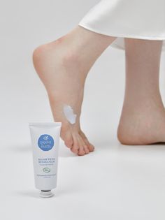 Bare feet with a dollop of foot balm and a tube of product on a white background