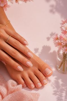 Hands and feet with manicured nails on a pink background with flowers