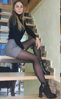 Woman in a black turtleneck and mini skirt sitting on wooden stairs