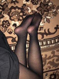 Legs in black tights resting on a patterned carpet