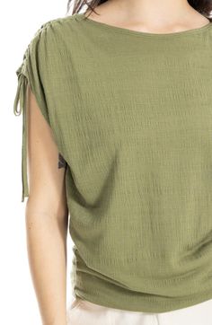 Woman wearing a green textured top with drawstring details on a white background