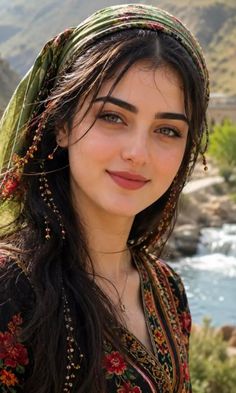 Woman with long dark hair and a green headscarf by a river