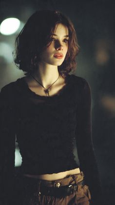 Woman with short hair and a dark top, showing exposed midriff