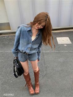 Woman in a denim shirt and shorts with brown boots and a black handbag outdoors
