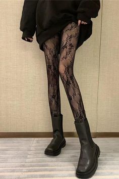 Person wearing lace tights and black boots with an oversized top indoors