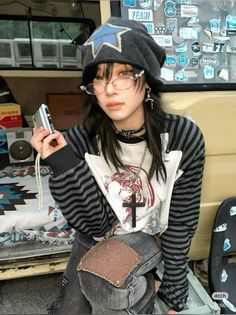 Person in a beanie and striped shirt holding a camera indoors