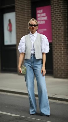 Woman with blonde hair and sunglasses wearing a white shirt and light wash jeans