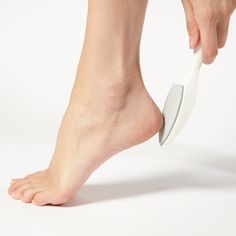 Person using a pumice stone on their heel against a white background