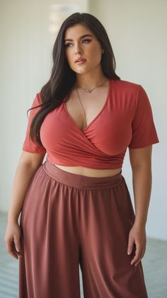 Woman with long dark hair wearing a crop top and wide leg pants indoors