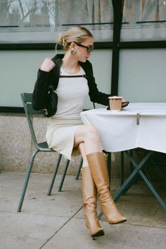 Woman with blonde hair and sunglasses sitting at an outdoor cafe table