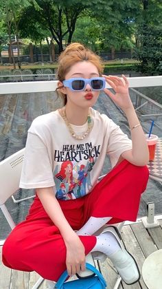 Woman in red pants and a graphic t-shirt wearing sunglasses outdoors