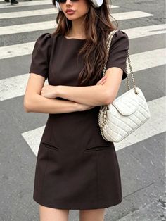 Woman in a brown dress with sunglasses and headphones on a crosswalk