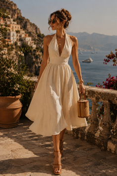 Woman in a cream halter dress walking along a coastal path with a straw bag