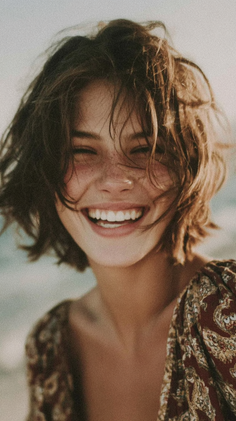 Woman with short hair and freckles smiling with eyes closed