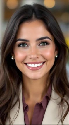 Smiling woman with long brown hair and green eyes wearing pearl earrings