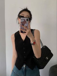 Woman in a black vest and sunglasses taking a selfie indoors