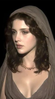 Woman with long wavy hair wearing a hooded dress and necklace, soft lighting