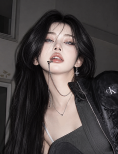Woman with long black hair and jewelry in a dark setting
