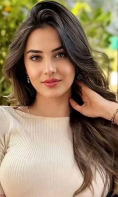 Woman with long brown hair wearing a ribbed top and jewelry outdoors