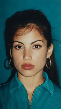 Woman with dark hair and hoop earrings wearing a teal shirt