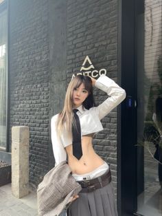 Woman in a cropped school uniform shirt and skirt posing outdoors