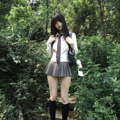 Person in a school uniform with a pleated skirt standing in a forest