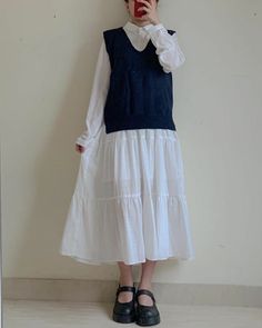 Person in a white dress and sleeveless sweater taking a mirror selfie