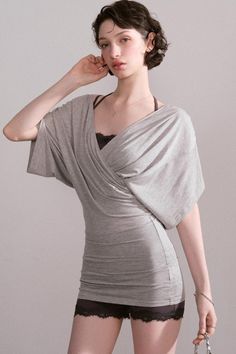 Woman with short hair wearing a gray top and black lace shorts