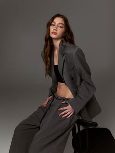 Woman in a gray suit jacket and black crop top in a studio