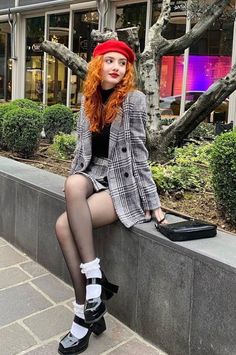 Woman with red curly hair wearing a plaid suit and red beret outdoors