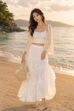 Woman in a white outfit and straw bag on a beach at golden hour