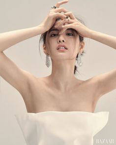 Woman in a strapless top with feather earrings and hands on her head