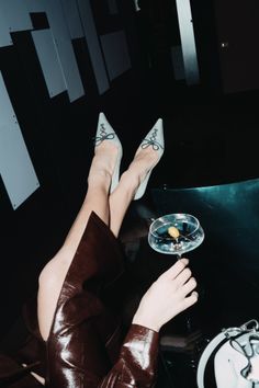 Person in high heels holding a martini glass with legs crossed