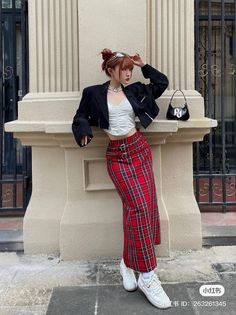 Woman in a red plaid skirt and cropped jacket posing outdoors